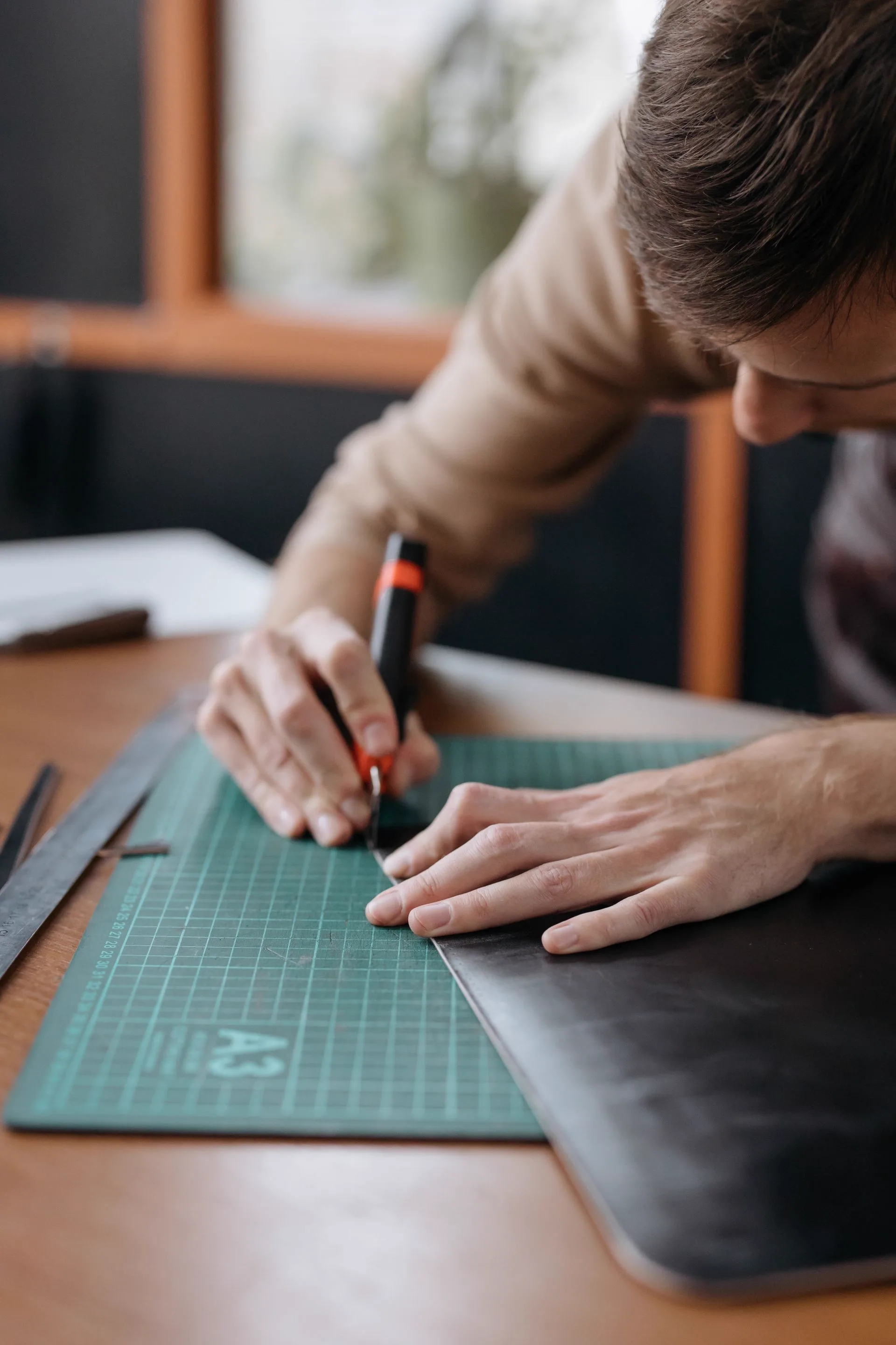Close-up of a craft knife following a ruler across a cutting mat